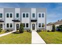 Modern townhome exterior shows neutral paint and well-maintained landscaping, including green grass and healthy plants at 3402 E 28Th Ave # 7, Tampa, FL 33605
