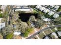 Aerial view showcasing a house nestled in a neighborhood with a pond and mature trees at 405 Manor Blvd, Palm Harbor, FL 34683