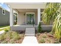 Inviting front porch featuring vibrant green double doors, modern lighting, and lush landscaping at 410 W Paris St, Tampa, FL 33604