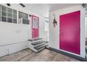 Exterior back door with gray steps, a pink storm door, and a large pink storage door at 4851 W Gandy Blvd # B3L35, Tampa, FL 33611