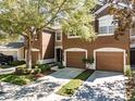 Two-story townhome with brown exterior, attached garages, landscaping, and mature trees at 4910 Pond Ridge Dr, Riverview, FL 33578