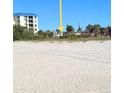 Sandy beach scene with condo building and trees in the background near the ocean at 7050 Sunset Way # 26, St Pete Beach, FL 33706