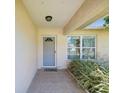 Covered front entrance featuring tiled flooring and complemented by lush landscaping at 803 Helmsman Way, Palm Harbor, FL 34685