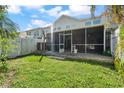 View of the backyard featuring a screened-in patio, green lawn, and white privacy fence at 914 Woodbridge Ct, Safety Harbor, FL 34695