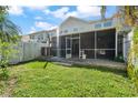 A view of the backyard showing the screened-in patio with lush lawn at 914 Woodbridge Ct, Safety Harbor, FL 34695