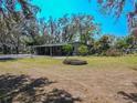 Large grassy backyard featuring a fire pit and shade trees at 12303 Greenland Dr, Riverview, FL 33579