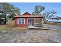 Exterior of red cottage-style home with ramp, set in a partially cleared lot at 15 Shore Dr, Palm Harbor, FL 34683