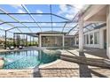 A lavish in-ground pool with screen enclosure, stone pavers, and an outdoor dining area with stone fireplace at 16312 Palmettoglen Ct, Lithia, FL 33547