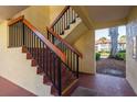 Hallway stairs featuring dark metal railing with wood trim and neutral colored stucco walls at 1712 Hammock Pine Blvd # 1712, Clearwater, FL 33761