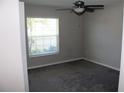 A cozy bedroom featuring gray walls, a ceiling fan, carpeted floor, and a window for natural light at 17152 Sunshine Mimosa St, Wimauma, FL 33598