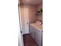 Functional laundry room featuring a washer, dryer, shelving, tiled flooring, and a convenient access door at 17152 Sunshine Mimosa St, Wimauma, FL 33598