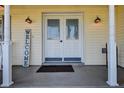 Welcoming front porch with double doors, decorative sconces, and a charming 'Welcome' sign at 18715 Lakeshore Dr, Lutz, FL 33549