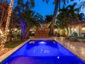 Beautiful backyard pool area with a tiki bar, lounge seating, and lush tropical landscaping at twilight at 238 31St N Ave, St Petersburg, FL 33704