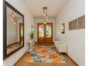 Elegant entryway featuring a floral rug, colorful glass front doors, modern lighting, and a stylish bench at 2660 Powell Ln, Tarpon Springs, FL 34688
