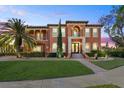 Stunning two-story home features a terracotta facade, lush landscaping, and a grand entrance at dusk at 5910 La Rosa Ln, Apollo Beach, FL 33572