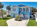 Charming two-story coastal home with vibrant blue exterior, elevated design, and manicured landscaping at 720 Bay Esplanade, Clearwater Beach, FL 33767