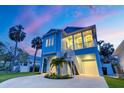 Charming two-story stilt home featuring a large porch and tropical landscaping, set against a twilight sky at 720 Bay Esplanade, Clearwater Beach, FL 33767