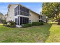 The backyard features lush green grass, manicured hedges, and screened-in patio on upper and lower levels at 12411 Eagleswood Dr # B, Hudson, FL 34667