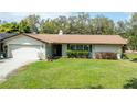 Traditional single-story home with a well-kept lawn, attached garage, and mature shrubbery at 1830 Oak Forest S Dr, Clearwater, FL 33759