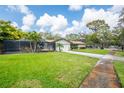 Charming home with lush landscaping, a screened-in lanai, and a long driveway at 1830 Oak Forest S Dr, Clearwater, FL 33759