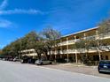 View of the building featuring balconies, mature trees, and convenient parking under a bright blue sky at 2226 Switzerland Way # 32, Clearwater, FL 33763