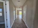 Inviting hallway with neutral walls, tiled floor, and doorways leading to various rooms at 2595 Wise River Ln, Zephyrhills, FL 33541