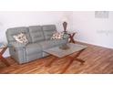 Cozy living room showcasing comfortable gray couch, glass coffee table, and wood laminate flooring at 8455 112Th St # 202, Seminole, FL 33772