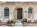 Welcoming home entrance featuring an arched entryway and meticulously maintained landscaping at 9845 84Th Way, Seminole, FL 33777