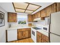 Functional kitchen with white appliances, wooden cabinets, and a window overlooking the yard at 3479 Maclaren Dr, Palm Harbor, FL 34684