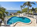 Backyard featuring a beautiful swimming pool, deck, and stunning waterfront views at 100 Driftwood W Dr, Palm Harbor, FL 34683