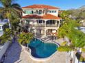 Aerial view of a two-story home highlighting the backyard pool, patio and lush landscaping at 100 Driftwood W Dr, Palm Harbor, FL 34683