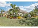 Beautifully landscaped front yard with lush green grass, colorful flowers and plants, and mature palm trees at 1503 Yale Castle Ct, Ruskin, FL 33570