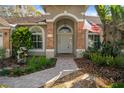 Inviting front entrance featuring a charming brick archway, manicured landscaping, and a decorative fountain at 17807 Crystal Cove Pl, Lutz, FL 33548