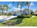Beautiful home exterior with lush landscaping, mature palm trees, and a two-car garage at 2082 Sifield Greens Way # 3, Sun City Center, FL 33573