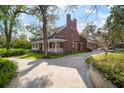 Side view of brick home showcasing a long driveway, mature trees, and manicured landscaping at 2906 Pemberton Creek Dr, Seffner, FL 33584