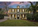 Inviting yellow two-story home with a covered front porch and well-manicured lawn at dusk at 2915 W Bay View Ave, Tampa, FL 33611