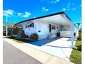 Bright home with white siding, carport, front porch and manicured landscaping on a sunny day at 34111 Alamanda N Dr, Pinellas Park, FL 33781