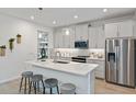 Bright kitchen with stainless steel appliances, quartz countertops, large island with bar seating, and stylish pendant lighting at 3475 Timber Crossing Ave, Brandon, FL 33511