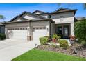 Attractive home with a three-car garage, stone accents, and well-manicured landscaping at 5006 Ivory Stone Dr, Wimauma, FL 33598