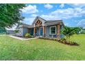 Inviting single-story home featuring a covered entry with wooden pillars and lush landscaping on a well-manicured lawn at 901 Eagle Ln, Apollo Beach, FL 33572