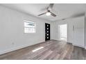 Bright living room featuring laminate flooring, a ceiling fan, a black front door, and fresh, white paint at 921 7Th Nw St, Largo, FL 33770