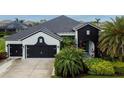 Two-story home showcasing black trim, a three-car garage and meticulous landscaping at 6927 Crestpoint Dr, Apollo Beach, FL 33572