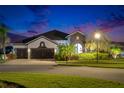 Charming two-story home boasting lush landscaping and a spacious three-car garage at twilight at 6927 Crestpoint Dr, Apollo Beach, FL 33572