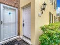 Close-up of the front door, featuring a decorative light fixture and the unit number on a stucco wall at 13719 Juniper Blossom Dr, Tampa, FL 33618