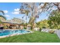 Spacious backyard with pool, lush lawn, privacy fence and mature trees at 230 Lotus Dr, Safety Harbor, FL 34695