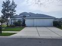 Beautiful single-story home featuring a well-manicured lawn, mature trees, and a three-car garage at 3215 Coconut Grove Rd, Land O Lakes, FL 34639