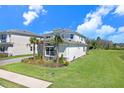 Attractive two-story home with white exterior, stone accents, and well-maintained landscaping, located near a pond at 32423 Rosewood Meadow Ln, Wesley Chapel, FL 33543