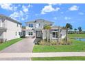 Charming two-story home with stone accents, a three-car garage and a brick paved driveway, located near a pond at 32423 Rosewood Meadow Ln, Wesley Chapel, FL 33543
