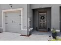 Townhome featuring gray front door with a wreath and attached one-car garage with black accents at 33064 Tulip Petal Ln, Wesley Chapel, FL 33545