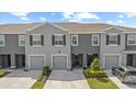 Two-story townhome showcasing a gray facade, garage, driveway, and manicured front lawn at 33064 Tulip Petal Ln, Wesley Chapel, FL 33545